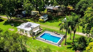 Ein Wohnhaus mit Schwimmbad, umgeben von üppiger Bepflanzung und einem gepflegten Rasen.