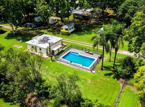 Una propiedad residencial con piscina, rodeada de exuberante follaje y un césped bien cuidado.