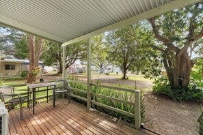 A covered outdoor area with a wooden deck, metal chairs, and a table.