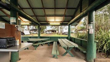 A covered picnic area with benches and a grill.