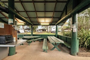 A covered picnic area with benches and a grill. - Tiny Away Stay – Mann River (Jackadgery)