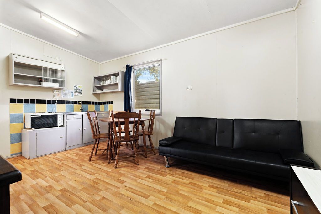Un espace de vie compact comprenant un coin repas, une kitchenette et un canapé noir.