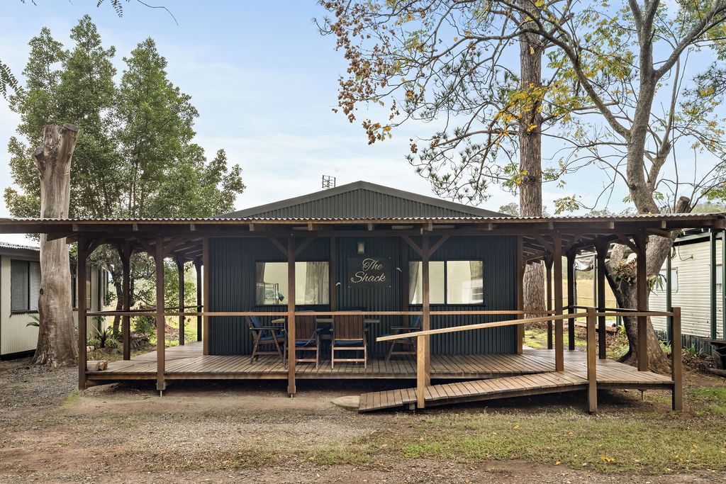 A wooden deck with a covered seating area and a sign reading 'The Shack.'