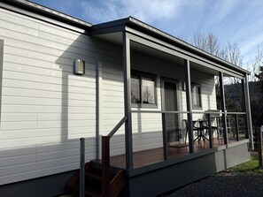 A modern house with a covered porch, a staircase, and a view of the surrounding landscape.