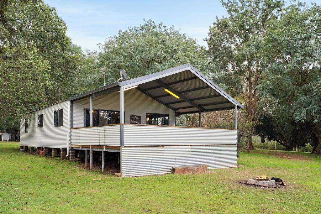 Een laag gebouwd metalen gebouw met een overdekte veranda en een bord waarop 'River Cottage' staat.