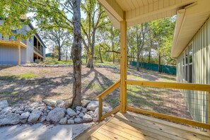 A covered wooden deck with a view of a residential area, including a house and a fenced yard. - Lakeside 2BR Cabin Table Rock Lake - Sunset Views (Eagle Rock)
