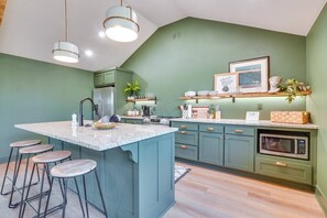 A modern kitchen with a central island, bar stools, a refrigerator, a microwave, and a coffee machine. - Lakeside 2BR Cabin Table Rock Lake - Sunset Views (Eagle Rock)