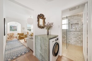 Un intérieur moderne comprenant un lave-linge, un miroir et un espace douche.