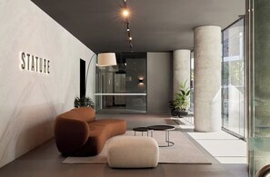 En moderne lobby med sofa, skærmpude og et skilt med 'STATURE'.