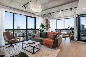 A modern living room with large windows, a sofa, a coffee table, and a view of the cityscape. - Skyline & Bay Views Stylish 3BR Southbank Retreat (Southbank)