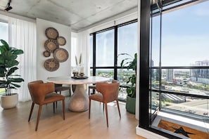 A modern dining area with a round table, two chairs, and a city view through large windows. - Skyline & Bay Views Stylish 3BR Southbank Retreat (Southbank)