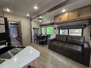 A compact RV interior with a kitchenette, dining area, and seating space. - Suite Escape on the Lake (Nevis)