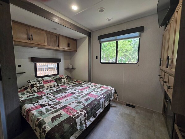 A bedroom with a bed, a window, and built-in wooden cabinets.