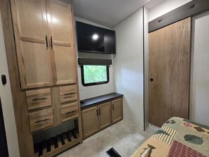 A compact kitchen with wooden cabinets, a built-in TV, and a window. - Suite Escape on the Lake (Nevis)