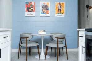 A modern kitchen with a round table, four grey chairs, and three colorful posters on the wall. - City Life Meets Quiet Comfort (Orlando)