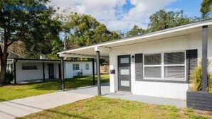 Ein eingeschossiges Haus mit überdachter Veranda, Garage und gepflegtem Rasen.