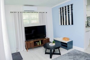 A living room with a flat-screen TV, a small round table, and a blue sofa. - City Life Meets Quiet Comfort (Orlando)