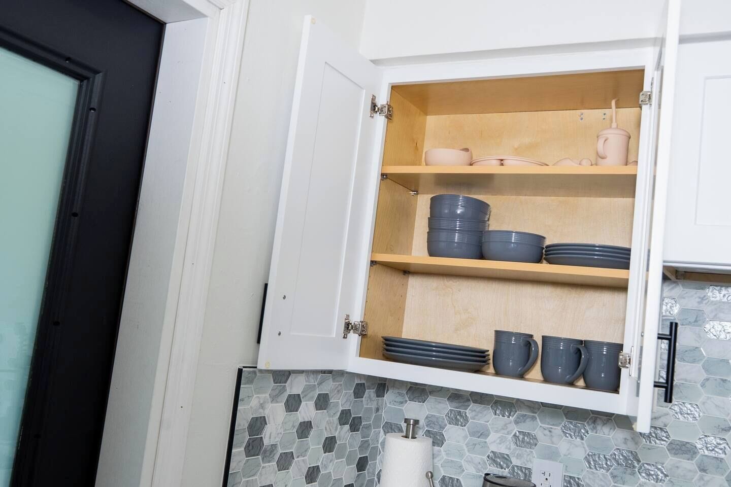 Una cocina con un armario que contiene platos, tazones y tazas.
