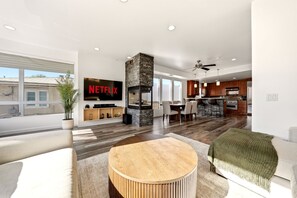 Un salon moderne avec une cheminée, un coin repas et une cuisine.