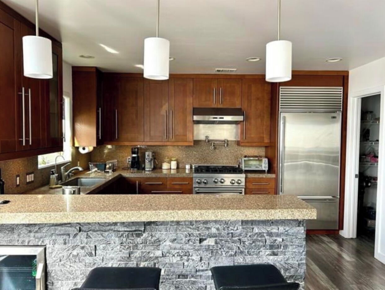 A modern kitchen with granite countertops, stainless steel appliances, and wooden cabinets.