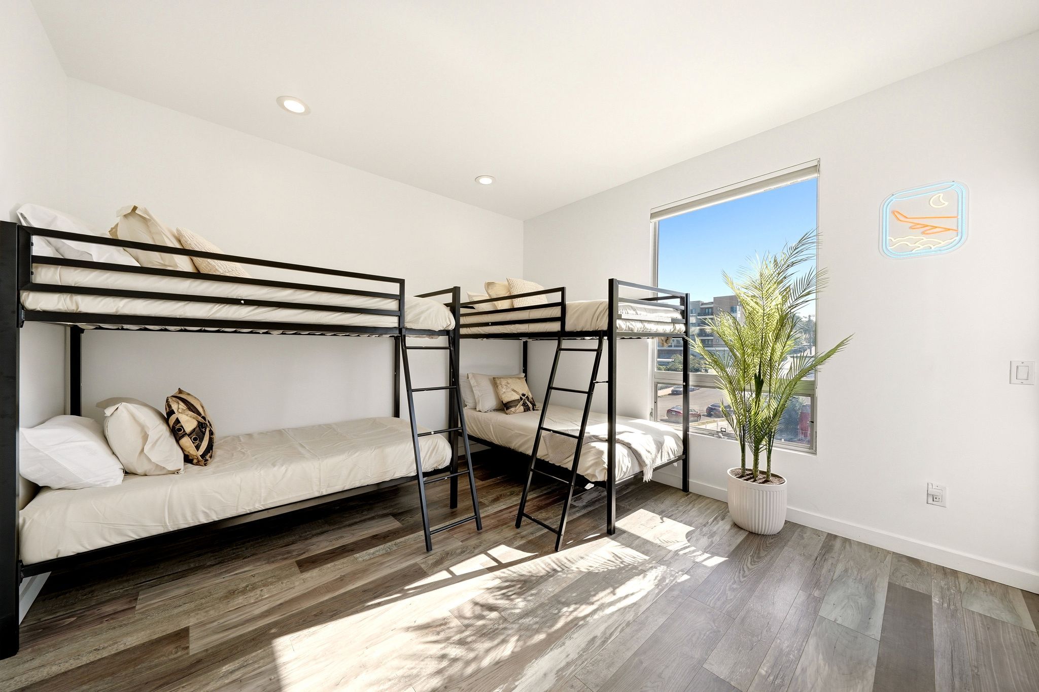 Un dormitorio moderno con literas, un ventanal grande y una planta en maceta.