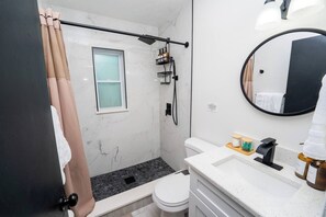 A modern bathroom with a shower, toilet, and sink. - Nomad Haven in Downtown: Recharge, Work & Explore (Orlando)