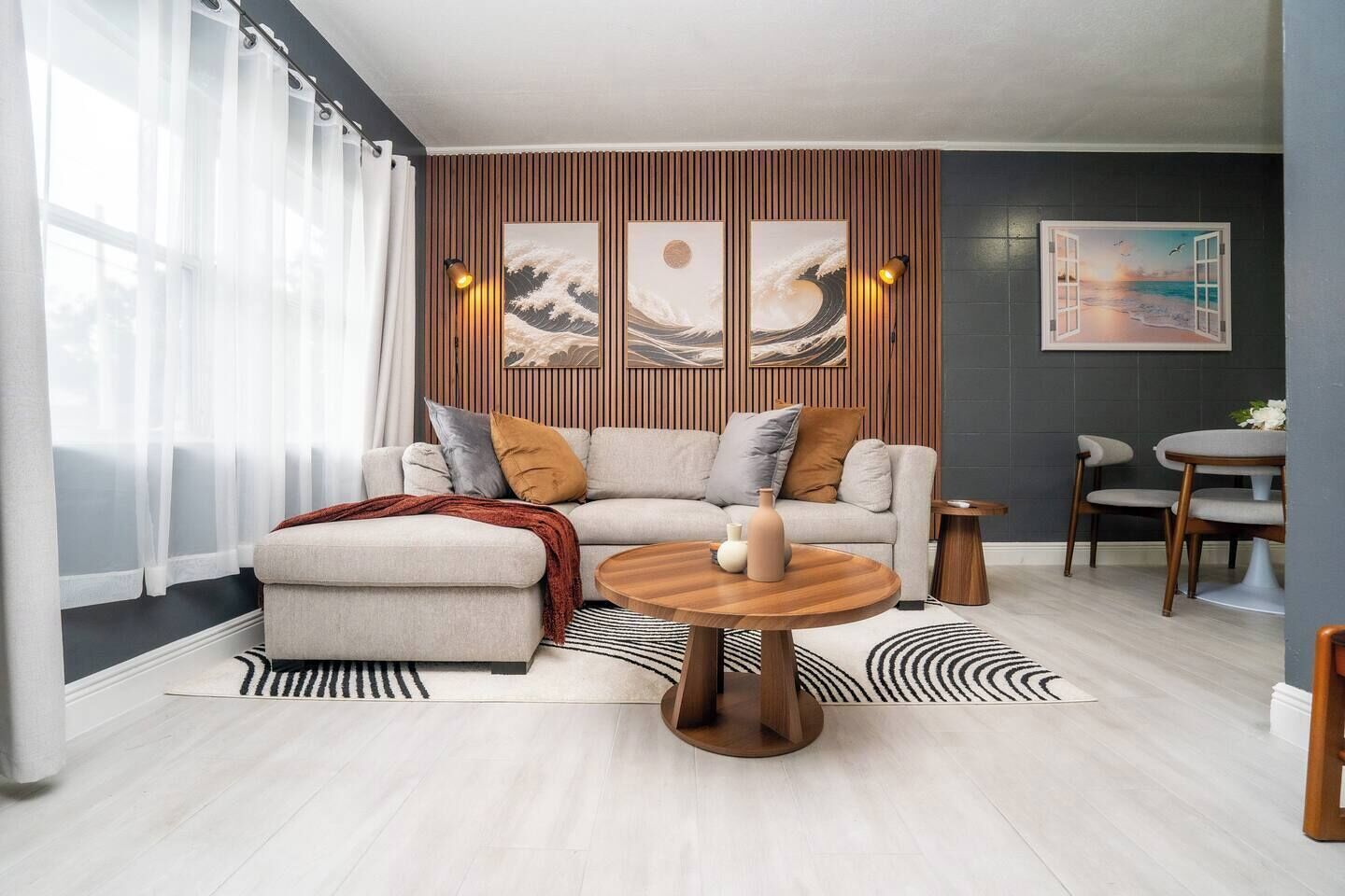 Ein modernes Wohnzimmer mit einer Eckcouch, einem runden Couchtisch und einem Essbereich mit zwei Stühlen.