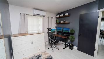 Un espacio de oficina moderno con un escritorio, dos monitores, una silla y una planta pequeña.