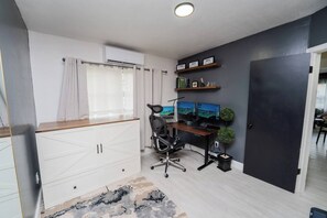 A modern office space with a desk, two monitors, a chair, and a small plant. - Nomad Haven in Downtown: Recharge, Work & Explore (Orlando)