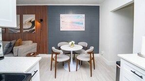Eine moderne Küche mit Essbereich, ausgestattet mit einer weißen Arbeitsplatte, Holzschränken und einem runden Tisch mit Stühlen.