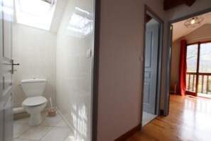 Ein Badezimmer mit Toilette, einer Duschkabine und einer Glastür, die auf einen Balkon führt.