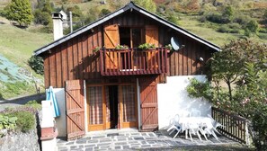 Eine Holzhütte mit Balkon, Steinstufen und Sitzgelegenheiten im Freien.