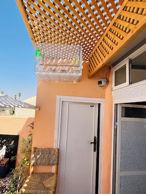 A room with a wooden lattice ceiling, a white door, and a window with decorative glass. - We Host 212 l Every Stay in Marrakech Worth Repeating (Marrakesh)