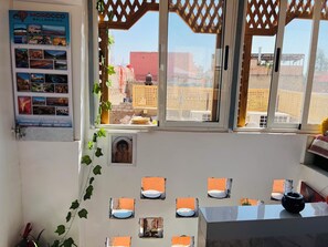 A room with a view of buildings outside, a poster on the wall, and a small window with a view of a cityscape. - We Host 212 l Every Stay in Marrakech Worth Repeating (Marrakesh)