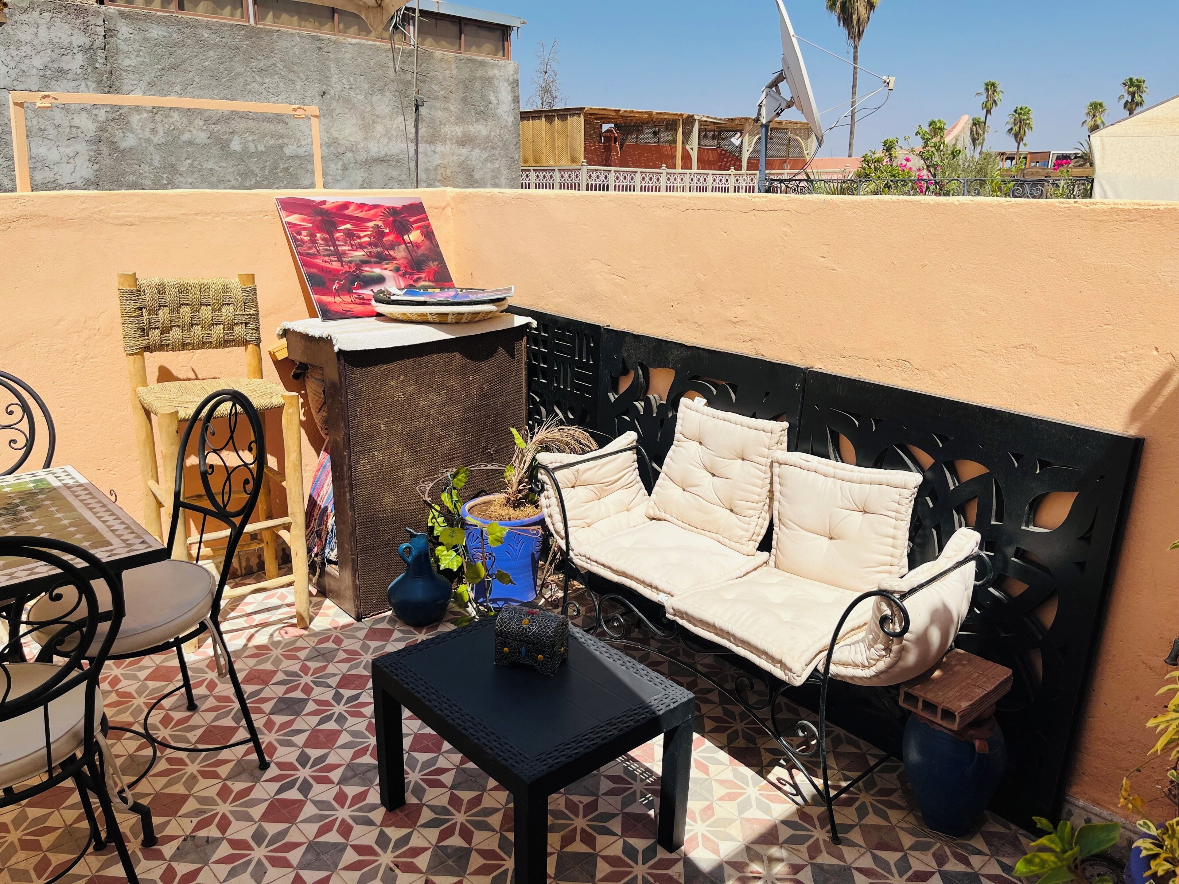 Une terrasse avec un canapé, des chaises, une petite table et un mur décoratif.