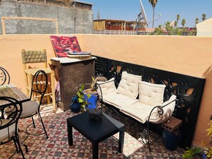 A patio with a sofa, chairs, a small table, and a decorative wall. - We Host 212 l Every Stay in Marrakech Worth Repeating (Marrakesh)