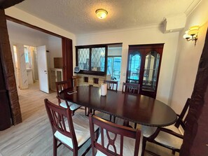 A dining area with a round table, wooden chairs, a clock, and a window with a view. - Ashford Luxury 4-bed Apartment (Ashford)