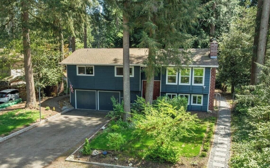 A two-story house with a garage, surrounded by trees and a well-maintained lawn.