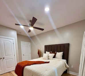 Un dormitorio con cama, ventilador de techo y dos puertas blancas.