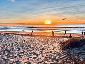 A beach with people walking along the shore during sunset. - L14 Luxury 3 Bedroom Apartment with views (Broadbeach)