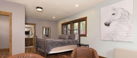 A bedroom with a bed, a window, a horse painting, and a chair.