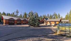 A lodge with a central building, a covered parking area, and a large evergreen tree. - Enormous Home! 6,000 SQFt! Hot Tub 6 Private Acres (Big Sky)