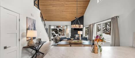 A modern kitchen with a marble countertop, a dining area with a sofa, and a large window with curtains.