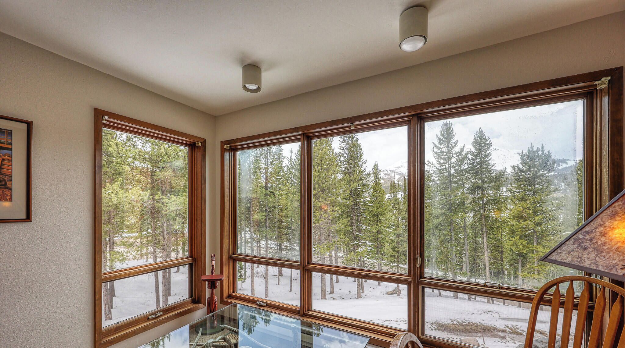 A room with large windows, a glass table, and a chair.