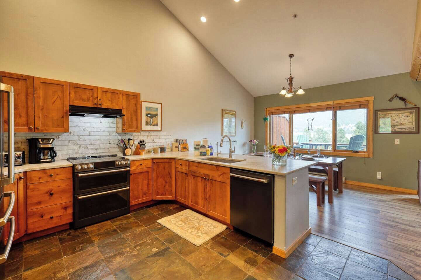 A kitchen with wooden cabinets, a built-in oven, a dishwasher, and a large island with a sink.