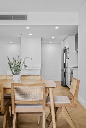 A modern kitchen with white cabinetry, a built-in oven, and a stainless steel refrigerator. - Luxurious 2BD Ocean View w/ Pool, Gym, Spa & Sauna (Surfers Paradise)