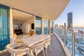 Ein Balkon mit Esstisch und Stühlen, einer Couch und Blick auf die Stadt.
