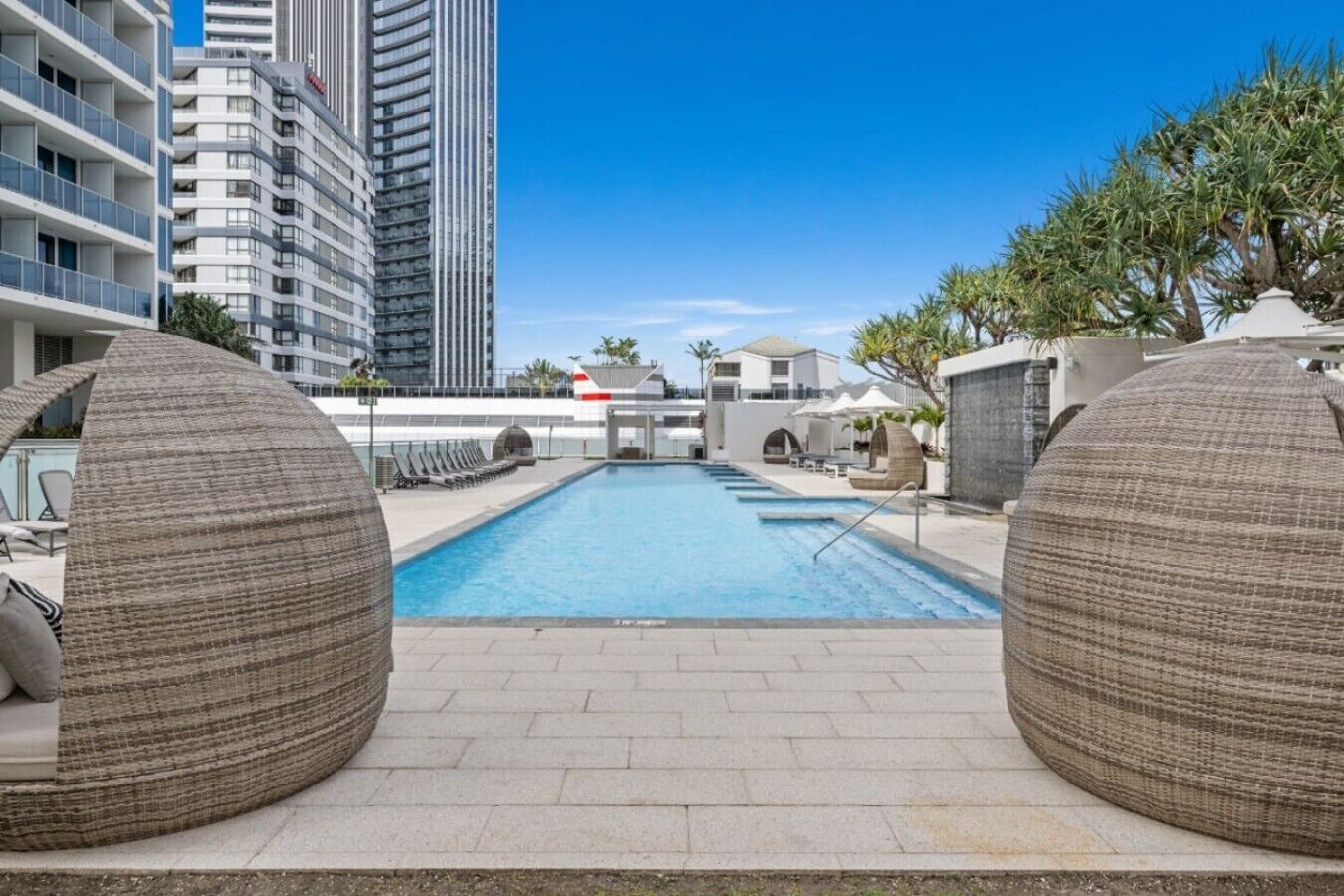 Une piscine dotée de chaises longues et offrant une vue sur les immeubles de grande hauteur.