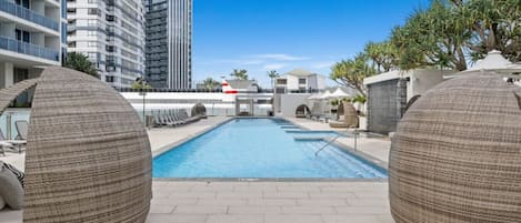 Une piscine dotée de chaises longues et offrant une vue sur les immeubles de grande hauteur.