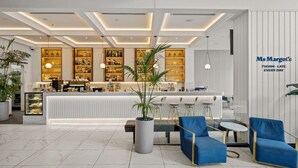 A modern bar area with a counter, bar stools, and a seating area with blue chairs. - Luxurious 2BD Ocean View w/ Pool, Gym, Spa & Sauna (Surfers Paradise)